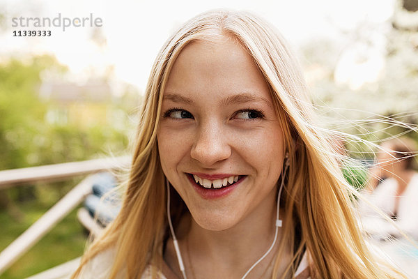 Fröhliches Teenagermädchen beim Musikhören im Hof