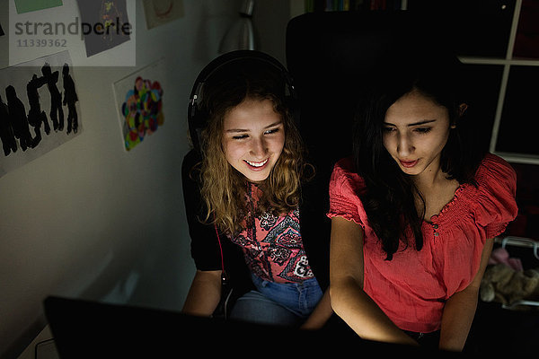 High-Winkel-Ansicht des glücklichen Teenager-Mädchens mit Computer mit Freund in der Dunkelkammer zu Hause