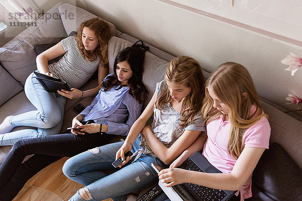 High-Winkel-Ansicht von Teenager-Mädchen mit Technologien beim Fernsehen im Wohnzimmer