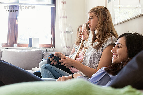 Fröhliche Teenagermädchen beim Fernsehen im Wohnzimmer zu Hause