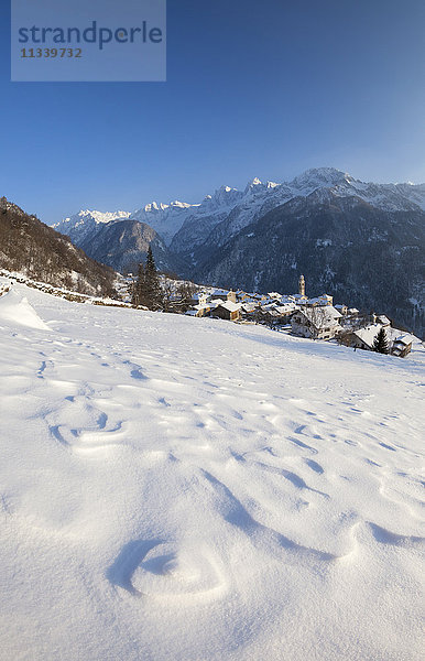 Sonnenuntergang über dem verschneiten Dorf Soglio  Bezirk Maloja  Bergell  Engadin  Kanton Graubünden  Schweiz  Europa