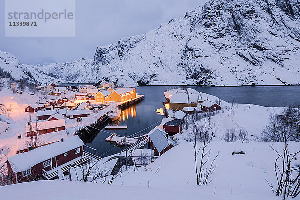 Lichter der Abenddämmerung auf dem Fischerdorf  umgeben von schneebedeckten Gipfeln  Nusfjord  Nordland  Lofoten  Nordnorwegen  Skandinavien  Europa