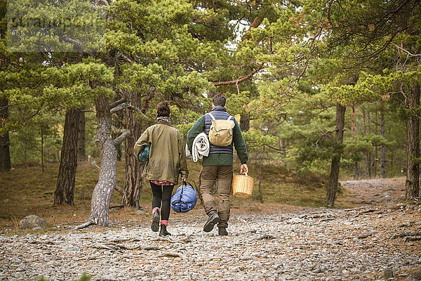 Rückansicht des Paares mit Schlafsäcken und Korb im Wald