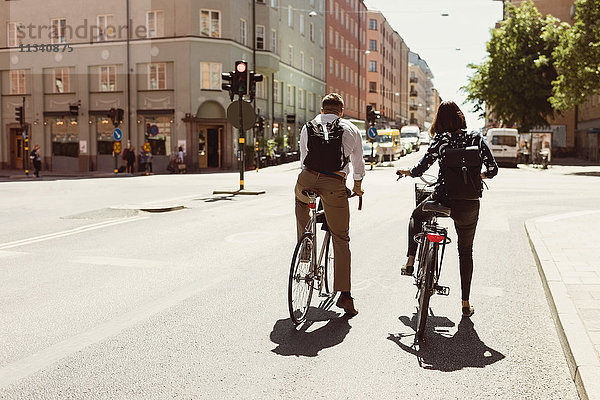 Rückansicht der Geschäftskollegen beim Radfahren auf der Stadtstraße