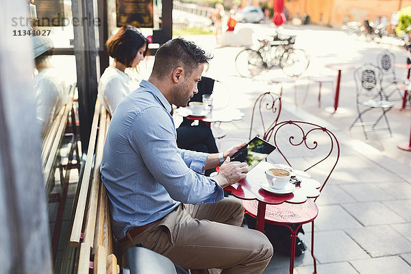 Geschäftsmann mit digitalem Tablett im Straßencafé