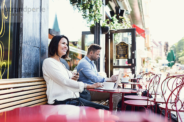 Nachdenkliche Geschäftsfrau  die ein Smartphone hält  während sie im Café sitzt.