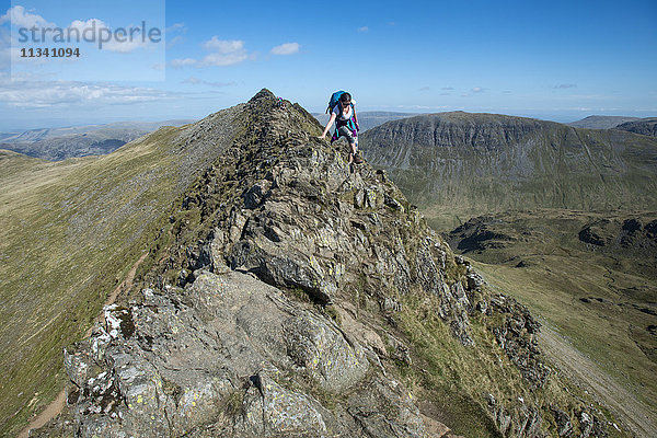 Eine Frau auf dem Gipfel des Striding Edge mit Blick auf den Ullswater im englischen Lake District  Lake District National Park  Cumbria  England  Vereinigtes Königreich  Europa