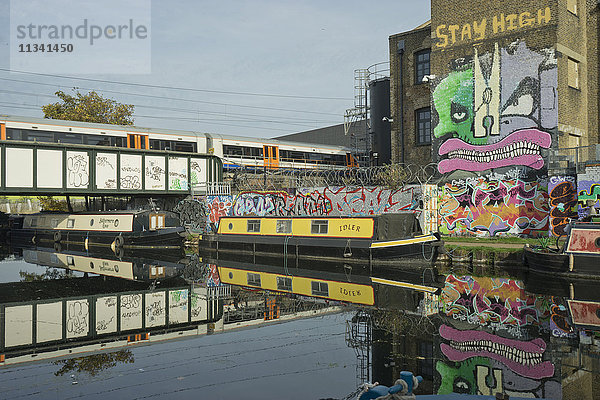 U-Bahn-Zug fährt am Kanal vorbei  vorbei an Künstlerateliers und Lagerhäusern in Hackney Wick  London  England  Vereinigtes Königreich  Europa