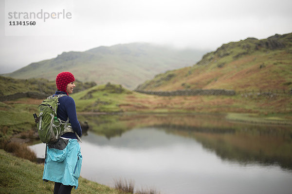 Eine Frau blickt auf Alcock Tarn in der Nähe von Grasmere  Lake District National Park  Cumbria  England  Vereinigtes Königreich  Europa