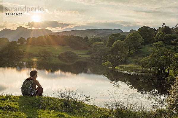 Eine Frau blickt auf den Loughrigg Tarn in der Nähe von Ambleside  Lake District National Park  Cumbria  England  Vereinigtes Königreich  Europa
