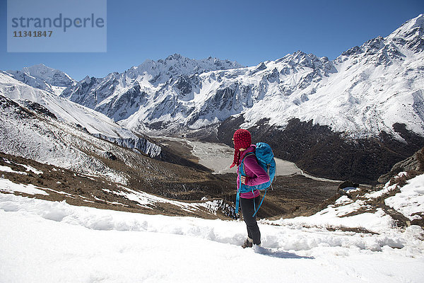 Ein Mädchen überblickt das Langtang-Tal vom Gipfel des Kyanjin Ri mit dem Gipfel des Ganchempo in der Ferne  Langtang-Tal  Himalaya  Nepal  Asien