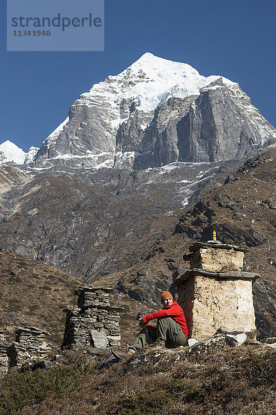 Ein Trekker hält neben einem Chorten an  um die Aussicht auf dem Weg zum Everest-Basislager mit Blick auf Taboche in der Ferne zu bewundern  Khumbu-Region  Himalaya  Nepal  Asien