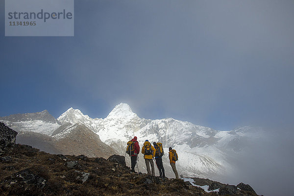 Ein Team von vier Bergsteigern macht sich auf den Weg zum Basislager der Ama Dablam  der 6856 m hohe Gipfel ist in der Ferne zu sehen  Khumbu-Region  Himalaya  Nepal  Asien