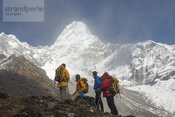 Ein Team von vier Bergsteigern macht sich auf den Weg zum Basislager der Ama Dablam  der 6856 m hohe Gipfel ist in der Ferne zu sehen  Khumbu-Region  Himalaya  Nepal  Asien