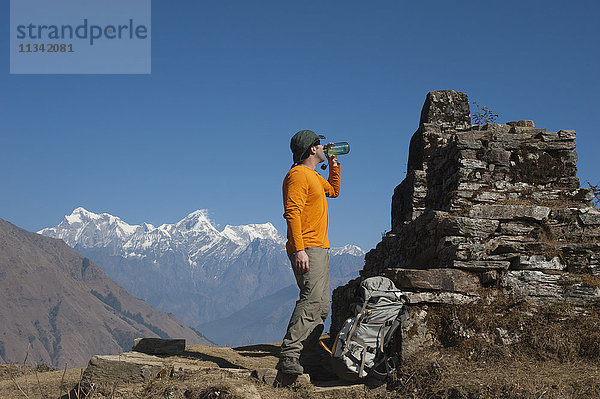 Ein Trekker nimmt eine wohlverdiente Erfrischung während der Manaslu-Rundwanderung  Himalaya  Nepal  Asien