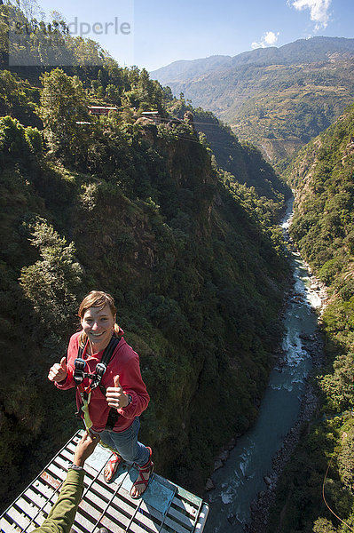 Ein Mädchen steht am Rand und bereitet sich auf einen Bungy-Sprung nach hinten vor  Nepal  Asien