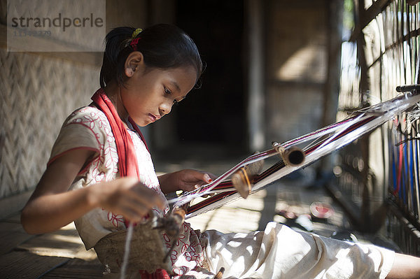 Ein kleines Mädchen erlernt die Kunst des Webens auf einem Handwebstuhl  Chittagong Hill Tracts  Bangladesch  Asien