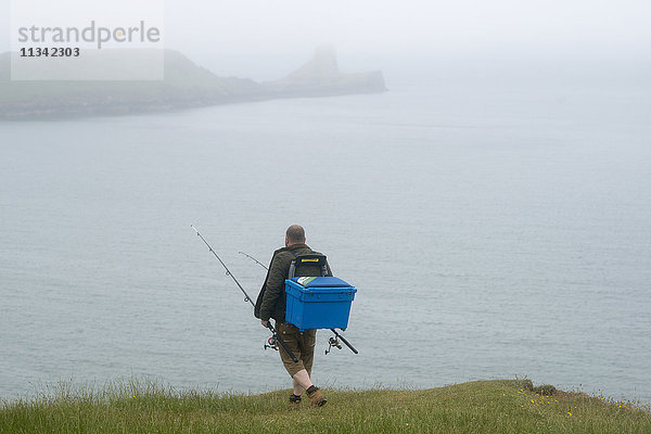 Ein Fischer geht von der Rhossili Bay am Gower in Südwales  Vereinigtes Königreich  Europa  in Richtung Worms Head.