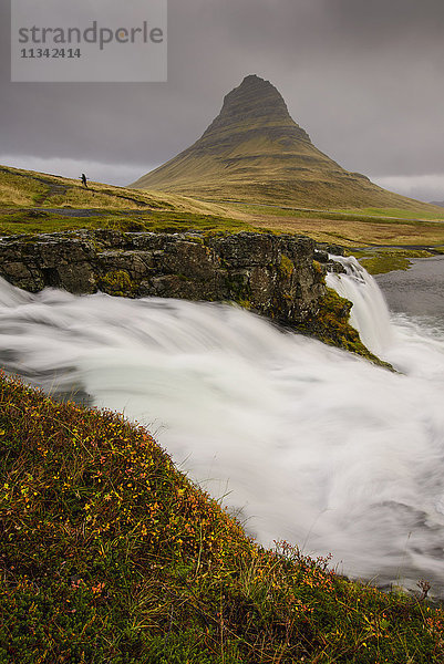 Kirkjufellsfoss im Herbst mit Wanderer  um den Maßstab zu zeigen  Island  Polarregionen