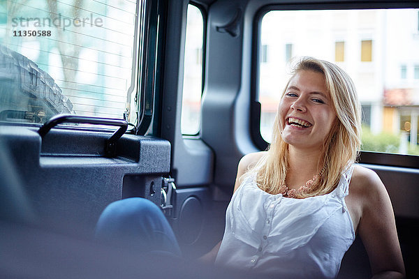 Portrait einer fröhlichen jungen Frau in einem Auto