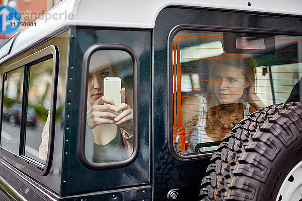 Zwei junge Frauen mit Handy in einem Geländewagen
