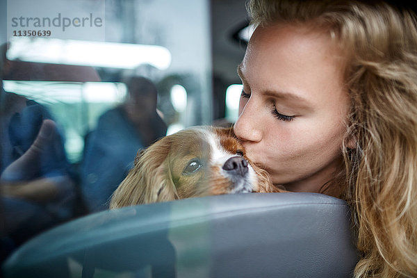 Junge Frau küsst einen Hund im Auto