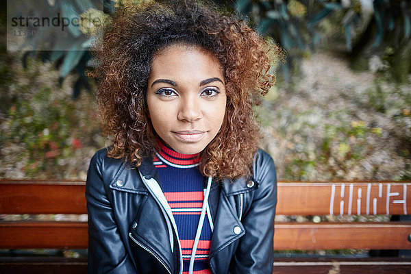 Portrait einer jungen Frau auf einer Parkbank