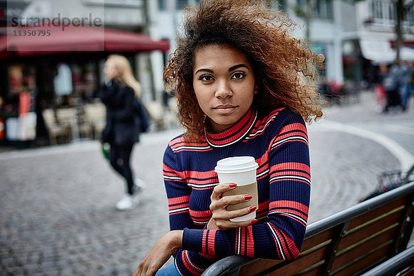 Portrait einer jungen Frau in der Stadt mit Coffee to go