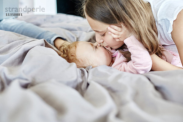 Mädchen küsst ein Baby im Bett