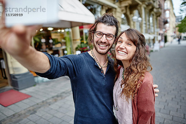 Lächelndes junges Paar macht ein Selfie in der Stadt