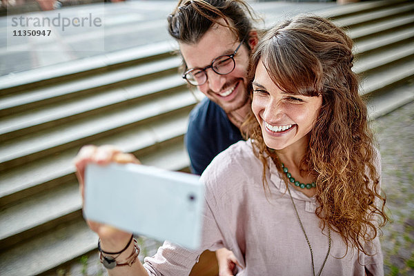 Lächelndes junges Paar macht ein Selfie im Freien