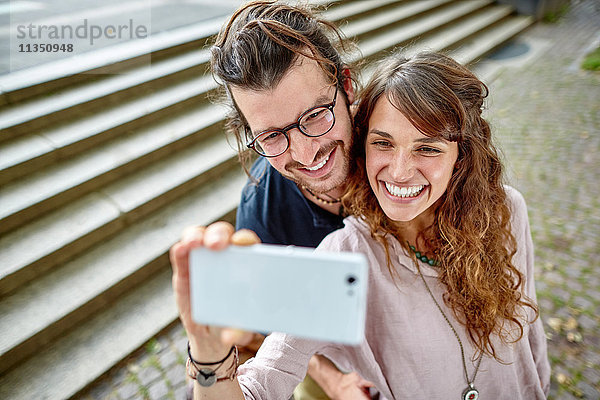 Lächelndes junges Paar macht ein Selfie im Freien