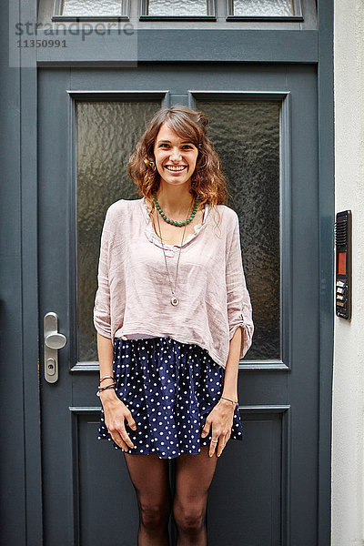 Portrait einer lächelnden jungen Frau an einer Tür