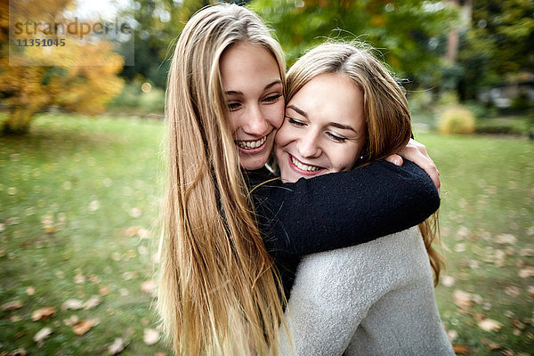 Zwei glückliche junge Frauen umarmen sich im Freien