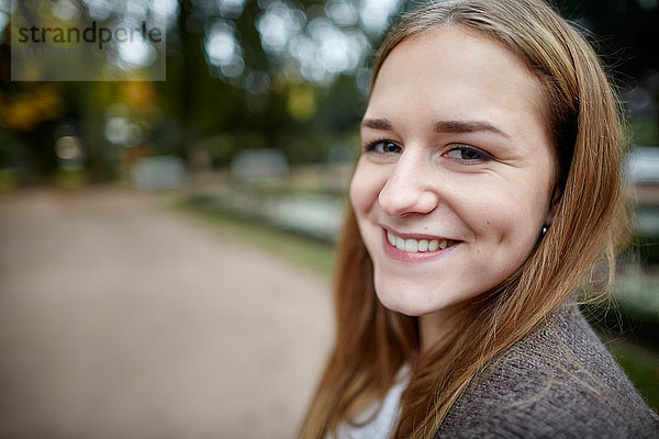 Portrait einer lächelnden jungen Frau im Freien