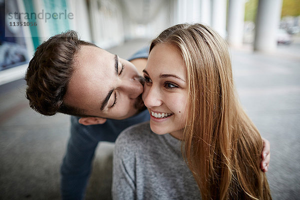 Glückliches junges Paar küsst sich im Freien