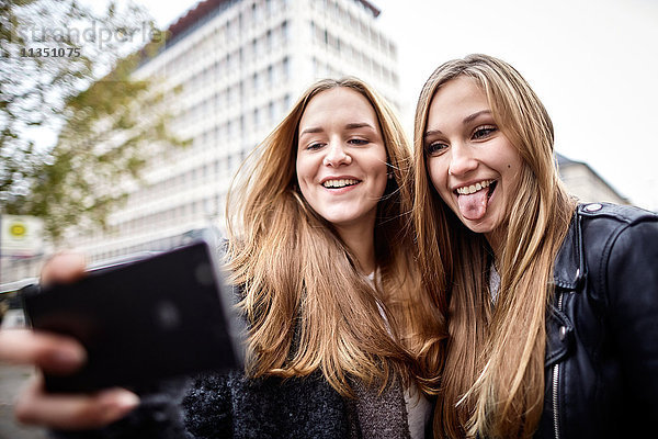 Zwei verspielte junge Frauen machen ein Selfie im Freien