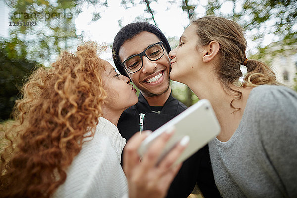 Drei lächelnde Freunde im Park machen ein Selfie