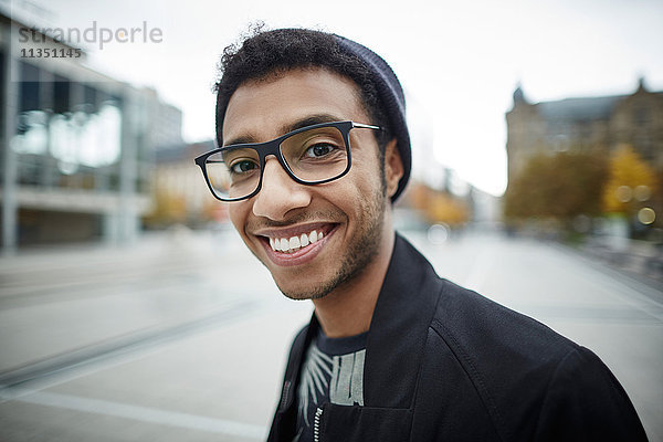 Portrait eines lächelnden jungen Mannes mit Brille im Freien