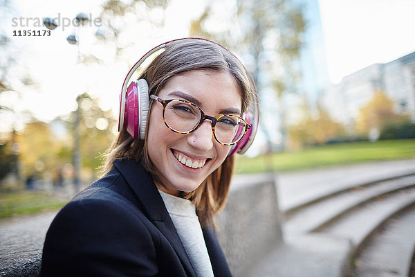 Portrait einer fröhlichen Frau mit Kopfhörern im Freien