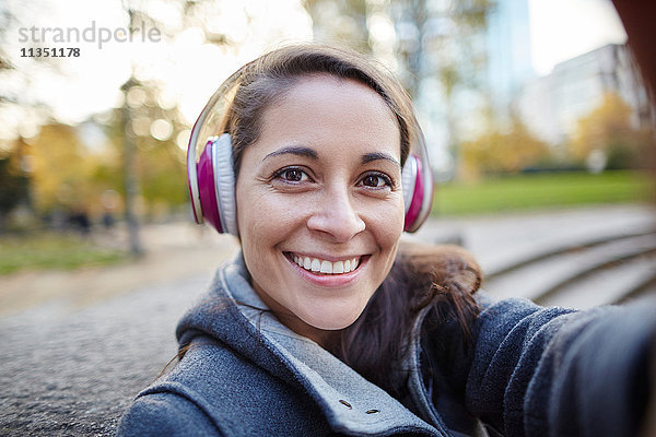Portrait einer lächelnden Frau mit Kopfhörern im Freien
