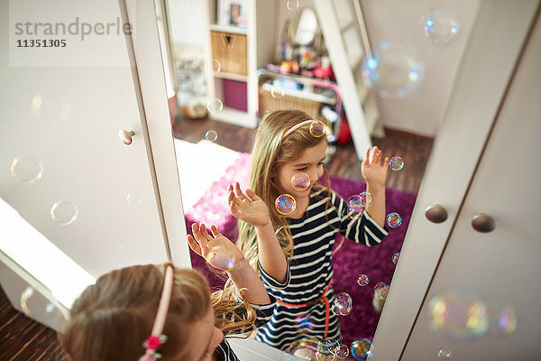 Glückliches Mädchen spielt mit Seifenblasen