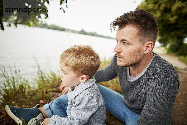 Vater und Sohn sitzen am Flussufer