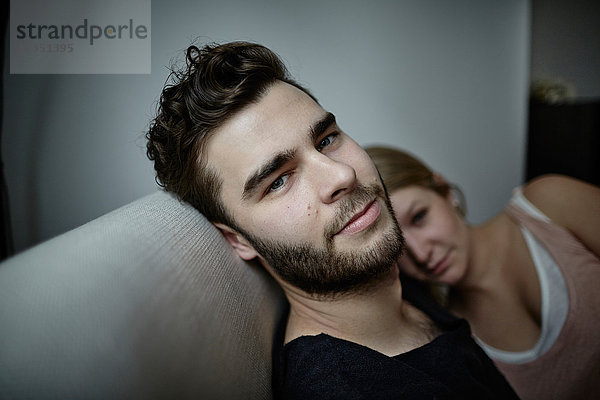Portrait eines jungen Mannes mit Freundin auf der Couch