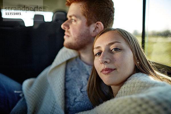 Junges Paar in einem Auto in eine Decke gewickelt