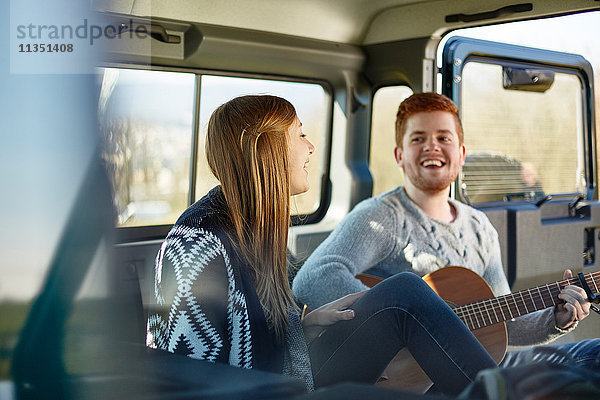 Fröhliches junges Paar macht Musik in einem Auto