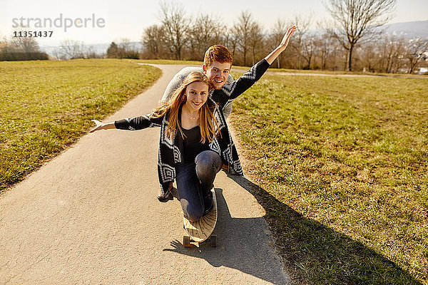 Junges Paar mit Skateboard auf einem Feldweg