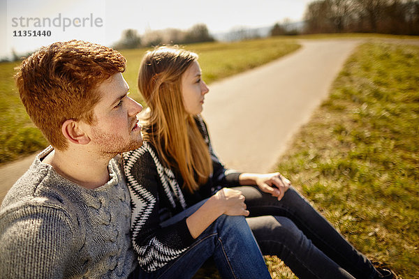 Junges Paar sitzt an einem Feldweg