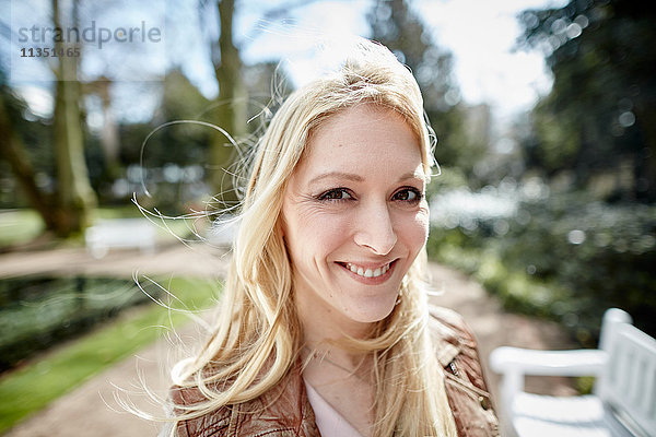 Portrait einer lächelnden jungen Frau im Park