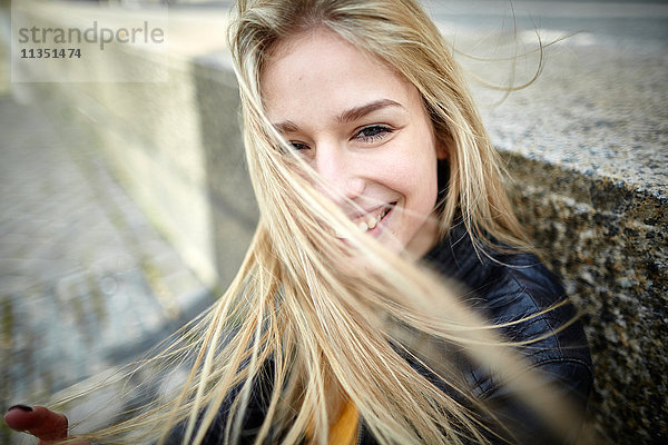 Portrait einer lächelnden jungen Frau mitwehendem Haar